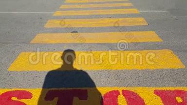 一个人站在行人过路处的<strong>开头</strong>，在那里停下来，等待经过的时间，在黄色的